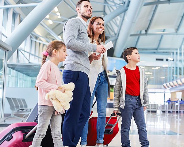 Eine junge Familie wartet voller Freude am Flughafen auf ihren Abflug in den Urlaub.