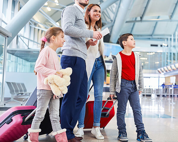 Eine junge Familie wartet voller Freude am Flughafen auf ihren Abflug in den Urlaub.