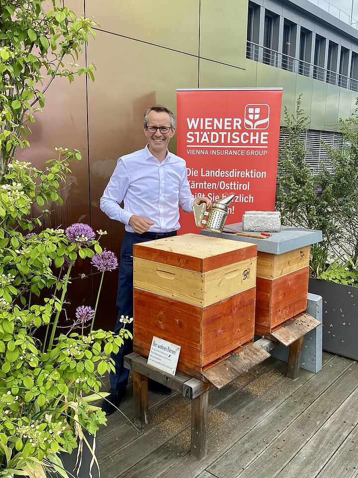 Mann steht vor einem Bienenstock.