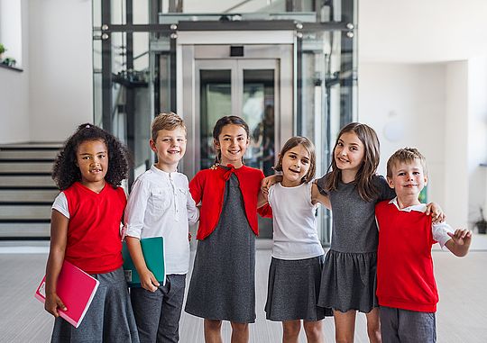 Mehrere Schulkinder stehen lächelnd nebeneinander und umarmen sich