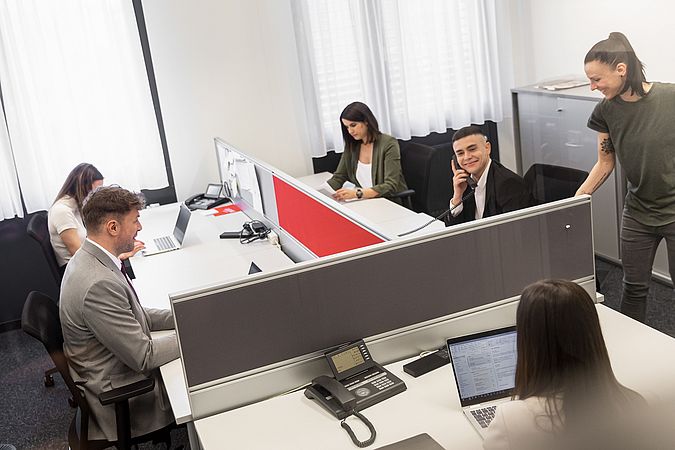 Fünf Personen am Schreibtisch in einem Bürozimmer. 