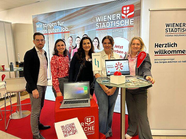 Gruppenfoto von fünf Personen auf einer Jobmesse vor einem Messestand mit digitalem Glücksrad.