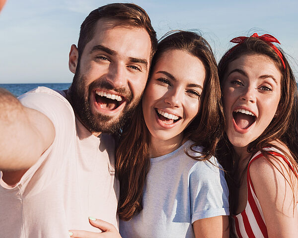 Eine Freundesgruppe macht voller Freude ein Selfie am Strand