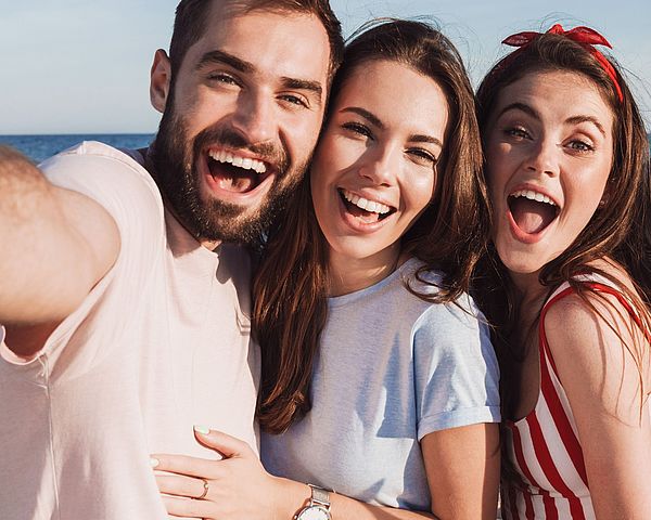 Eine Freundesgruppe macht voller Freude ein Selfie am Strand