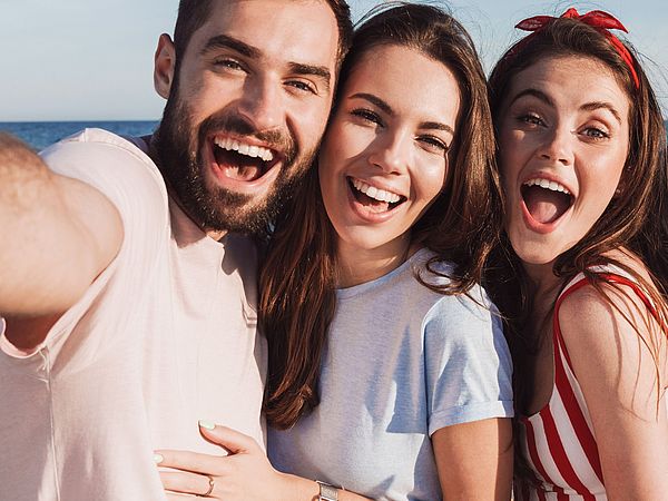 Eine Freundesgruppe macht voller Freude ein Selfie am Strand