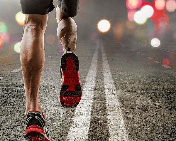 Ein Mann joggt auf einer Straße bei Dunkelheit