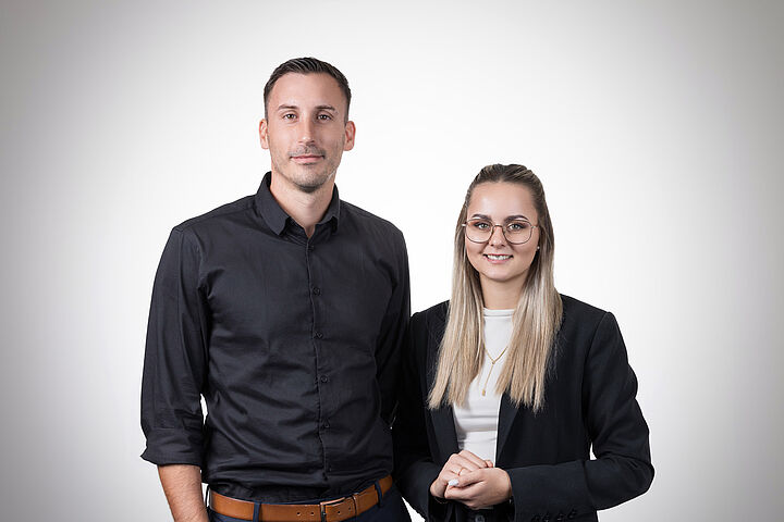 Auf dem Bild sieht man einen Mann und eine Frau im Businessoutfit