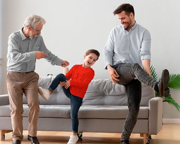 Drei glückliche Männer verschiedener Generationen tanzen im Wohnzimmer.