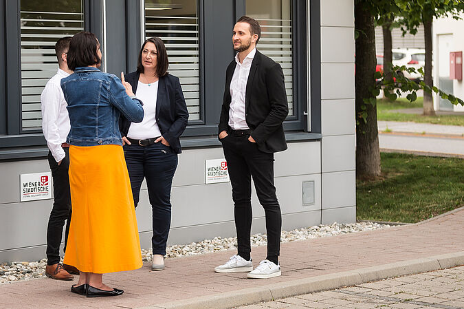 Mehrere Personen stehen beisammen und unterhalten sich.