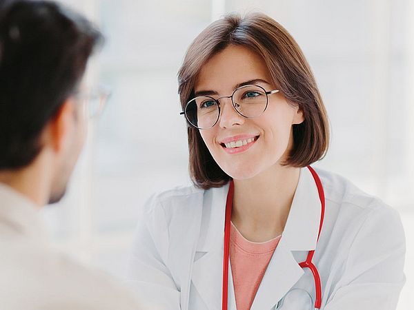 Eine junge Ärztin spricht mit ihrem Patienten.