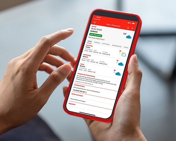 Ein Smartphone wird in der Hand gehalten während die Wetter Plus-App der Wiener Städtischen geöffnet ist.