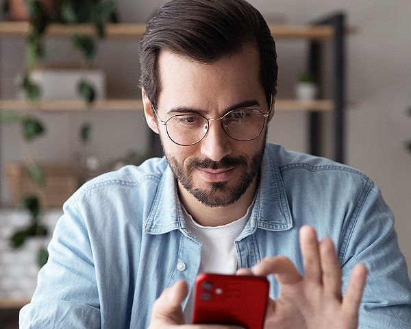Ein Mann hält ein Smartphone in der Hand und navigiert sich durch die Funktionen
