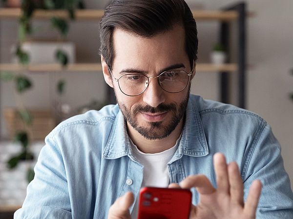 Ein Mann hält ein Smartphone in der Hand und navigiert sich durch die Funktionen