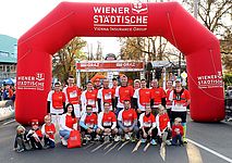 Eine Gruppe von Teilnehmerinnen und Teilnehmern steht nach absolvierten Graz Marathon im Ziel und jubelt voller Freude  