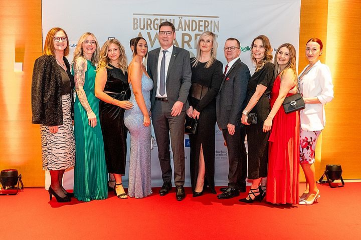 Gruppenfoto von zehn Personen in festlicher Abendgarderobe auf einer Gala.
