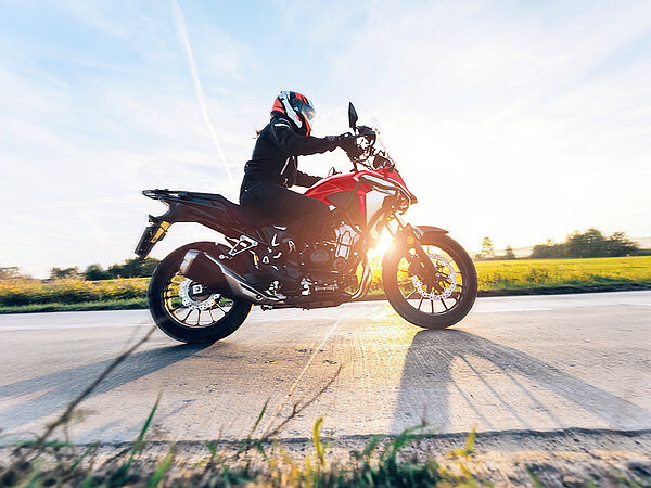 Ein Motorradfahrer fährt auf der Straße bei Sonnenuntergang.
