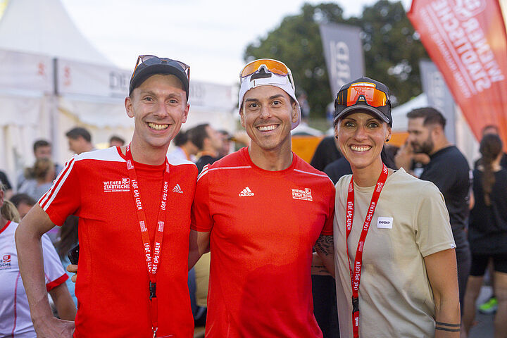 Drei Läufer lächeln beim Business Run fröhlich in die Kamera.