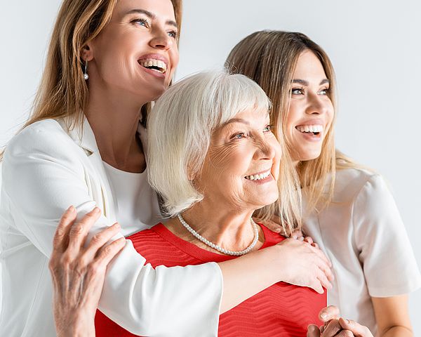 Drei glückliche Frauen verschiedener Generationen umarmen einander.