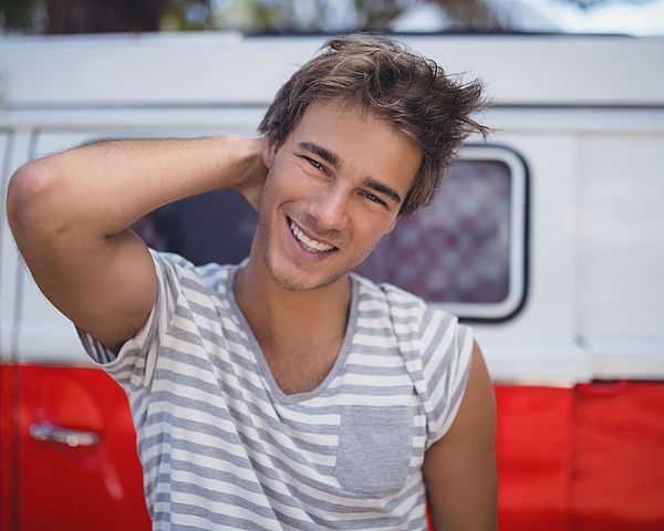 Porträt eines jungen Mannes, der vor einem Kleinbus steht.