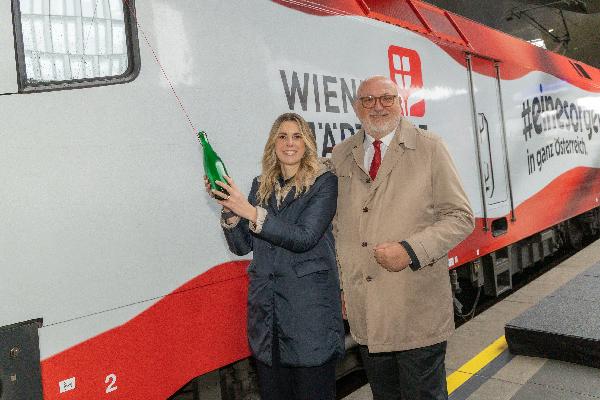 Zwei Personen bei der Einweihung einer neuen Lok am Bahnsteig.