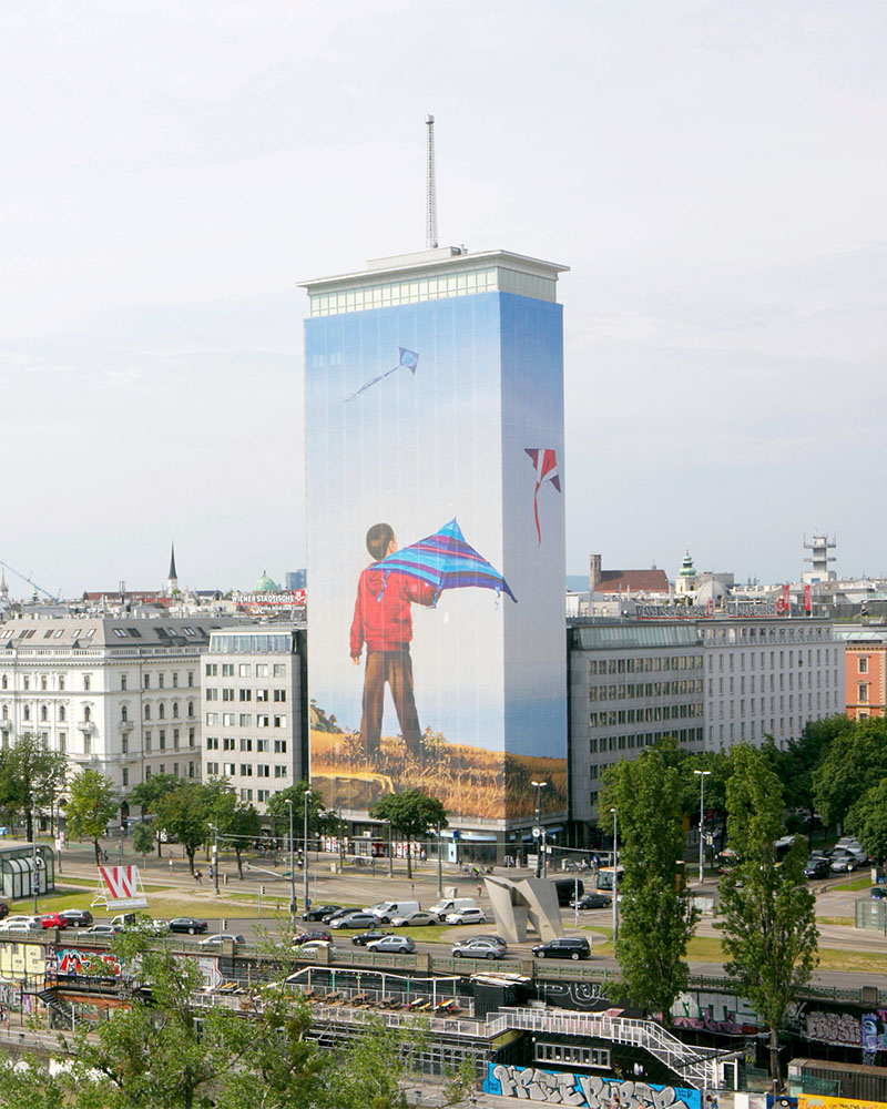 Bild vom Ringturm, wo die Fassade mit einer Abbildung eines Jungen, welcher Drachen steigen lässt, tapeziert ist. 